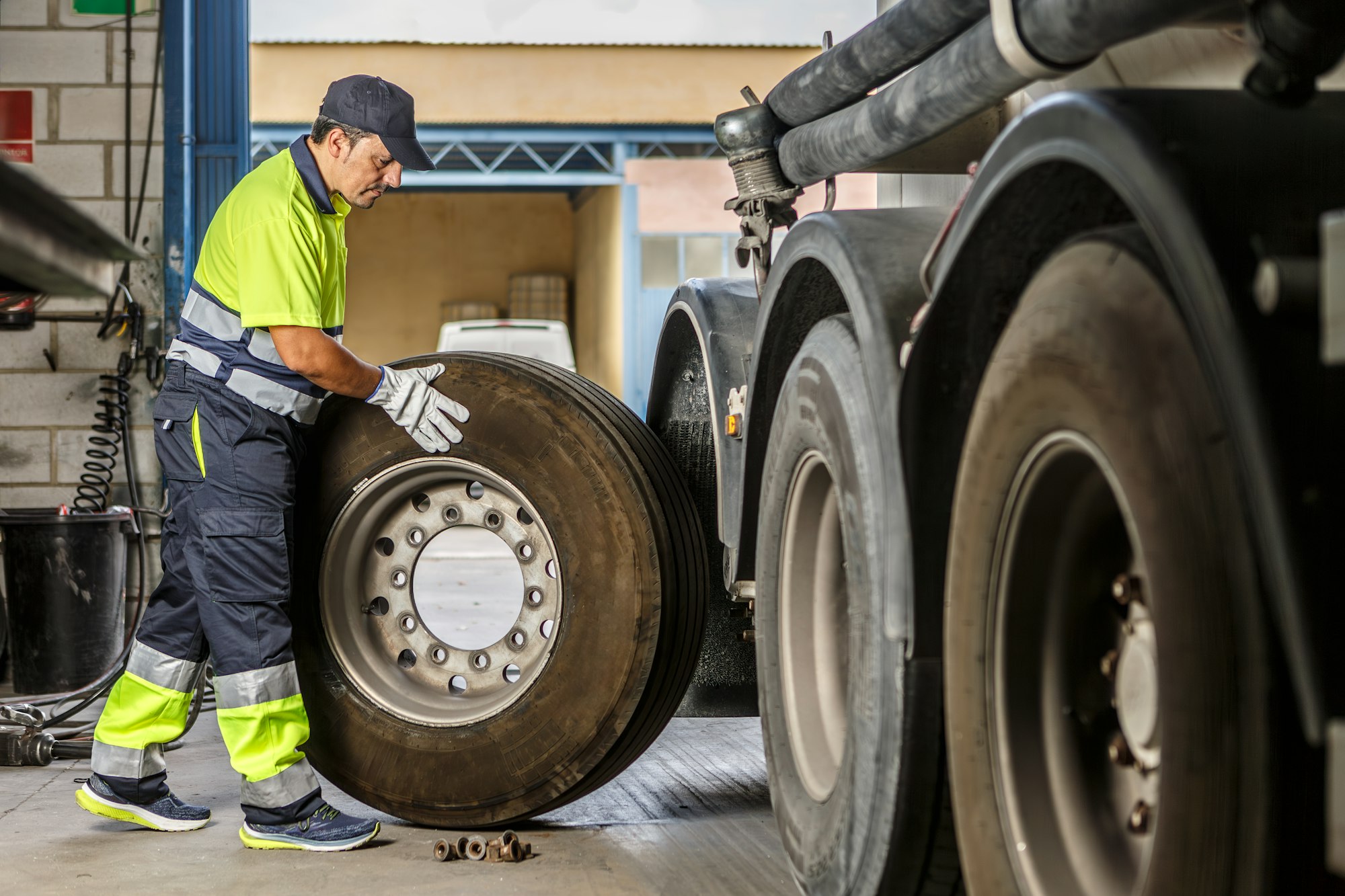 Male mechanic repairing truck wheel in workshop